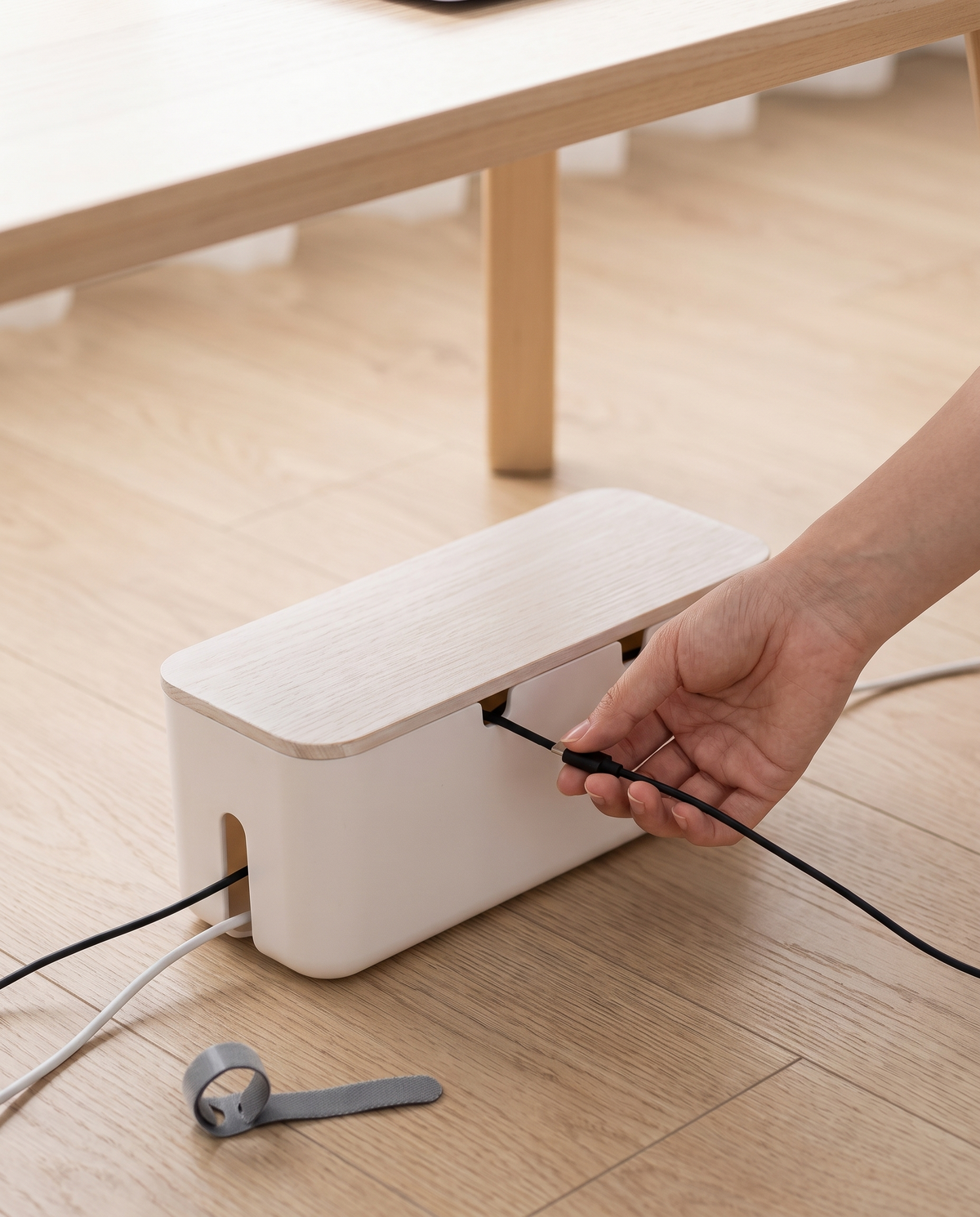 Caja organizadora de cables Vesta Home Hub blanca chica bajo escritorio, mano acomodando cable