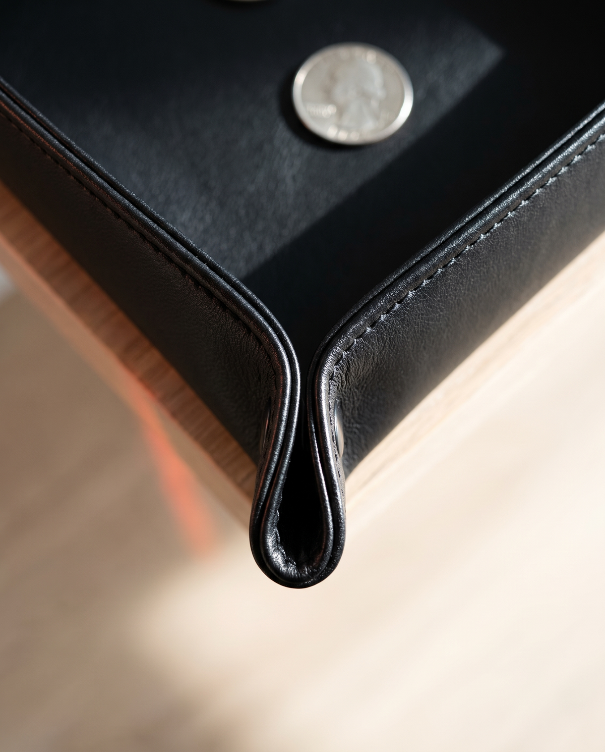 Detalle macro del pliegue y textura del cuero negro de la bandeja Vesta Home Hub